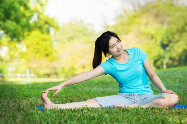 在绿色草地上瑜伽锻炼的年轻女人 — 图库照片