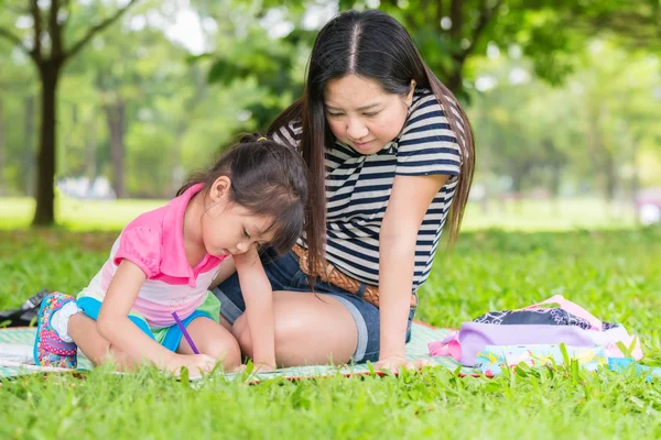 Petite fille dessinant avec sa mère allongée sur l'herbe — Photo