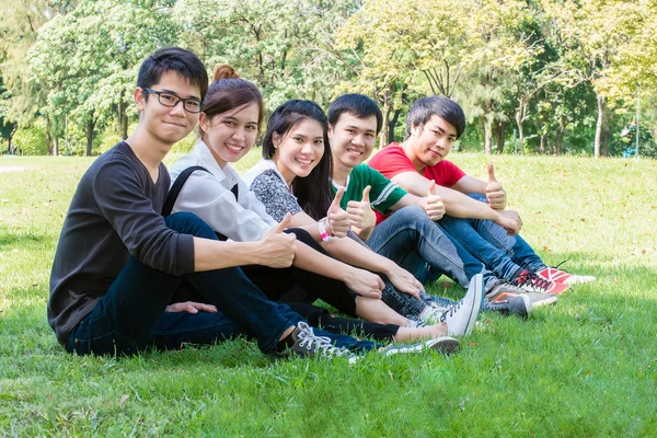 Öğrenci el başparmak kampüste otururken grup — Stok fotoğraf