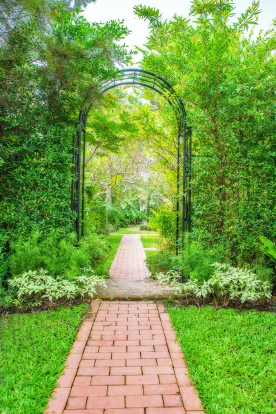 Giardino verde lussureggiante con pergolato in ferro battuto — Foto Stock