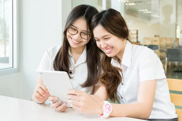 Dos estudiantes con uniforme en el aula con tableta electrónica —  Fotos de Stock