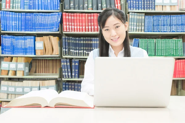 Estudiante asiático usando ordenador portátil en la biblioteca de la universidad —  Fotos de Stock