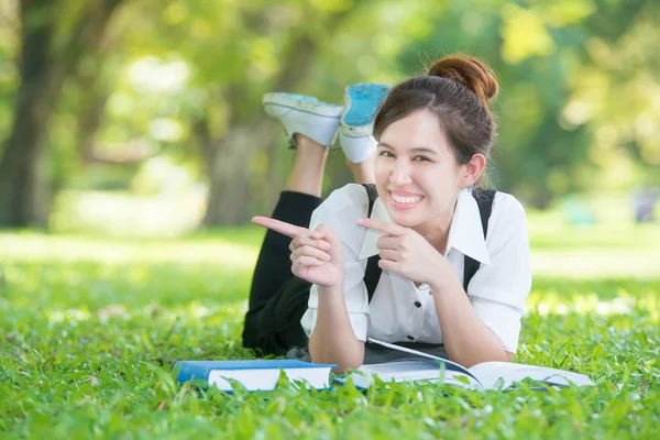 Asian young woman pointing in park — Stock Photo, Image