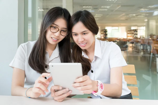 Dos estudiantes asiáticos con uniforme en el aula con tabl electrónico —  Fotos de Stock