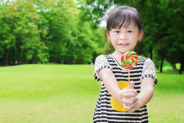 Asiática niña comiendo piruleta al aire libre en primavera parque — Foto de Stock