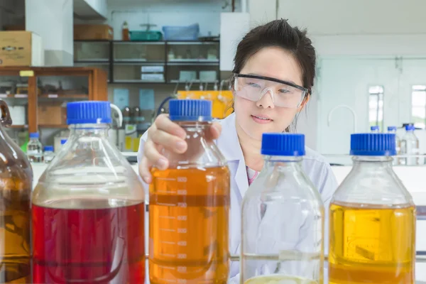 Cientista asiático selecionando garrafa na prateleira no laboratório — Fotografia de Stock