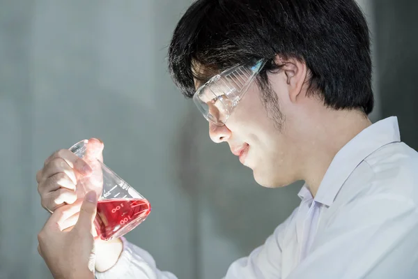 Азиатский ученый в белой форме работает в лаборатории — стоковое фото