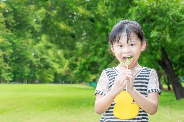 Asiatique petite fille manger sucette en plein air dans le parc de printemps — Photo