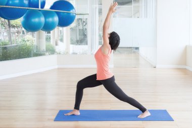 Asyalı kadın yapmak yoga savaşçı poz, sağ bacak öne, sol bacak