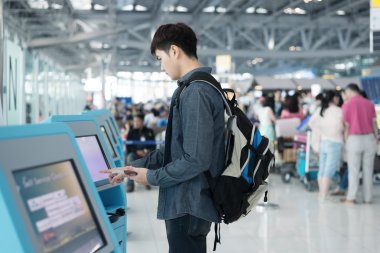Young asian man using self check-in kiosks in airport clipart