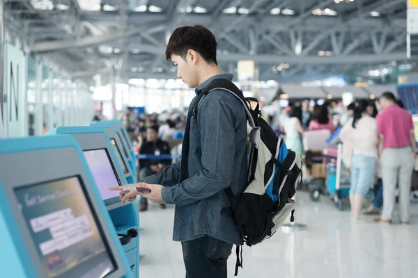 Jovem asiático homem usando auto check-in quiosques no aeroporto — Fotografia de Stock