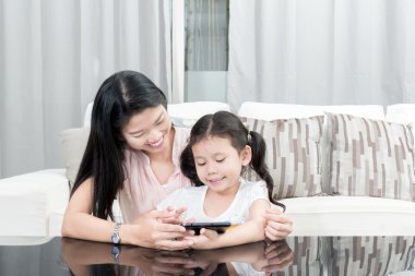 Asya anne ve kızı evde dijital tablet ile oynamak