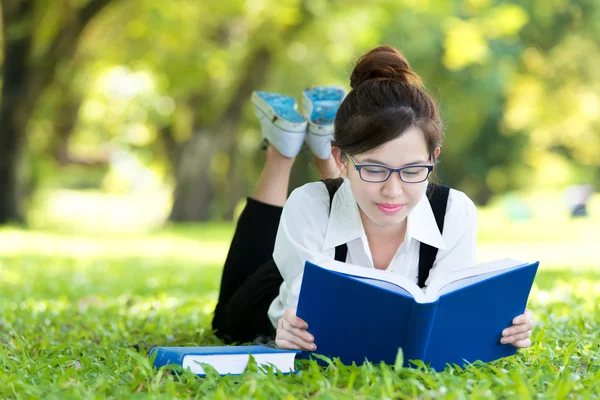 Sorrindo estudante casual deitado no livro de leitura de grama — Fotografia de Stock