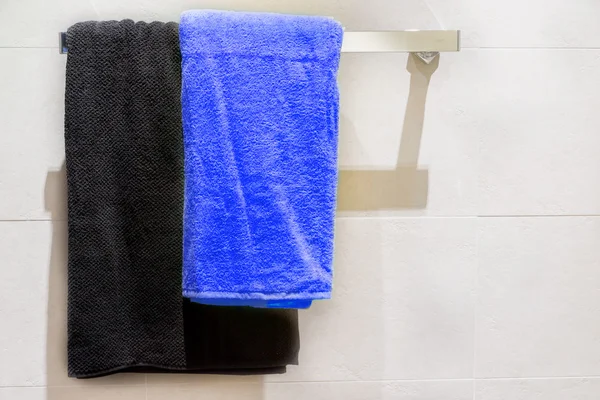 Black and blue towel on hanger in bathroom — Stock Photo, Image