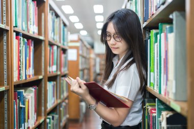 Asyalı öğrenci üniformalı Üniversitesi'nde kütüphanede okuma