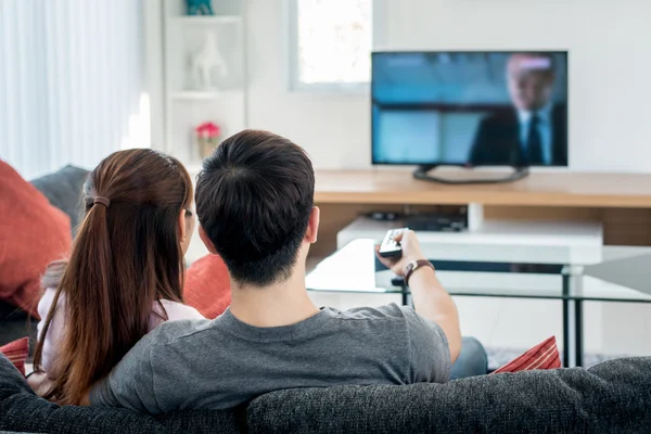 Bakifrån av asiatiska par titta på TV i vardagsrummet — Stockfoto