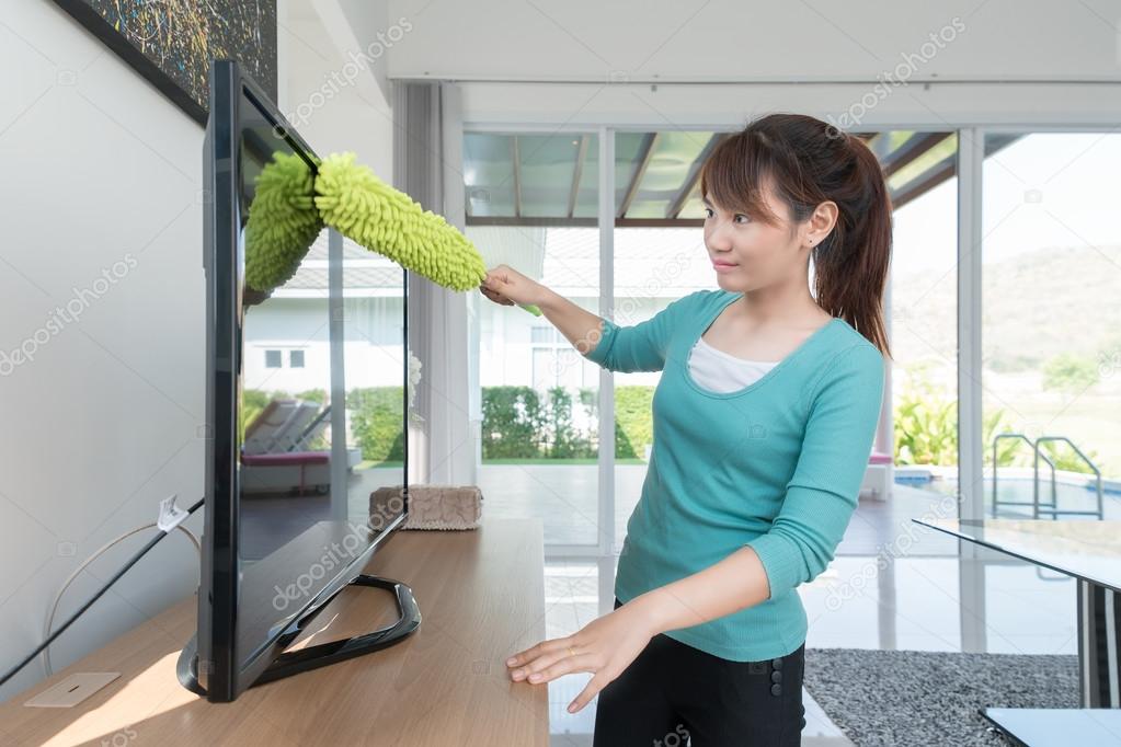 Asian young woman cleaning dust on TV at home