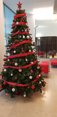 Noel, yeni yıl arifesi, çelenklerle süslenmiş köknar ağacı ve kırmızı ve gümüş renkli toplar.