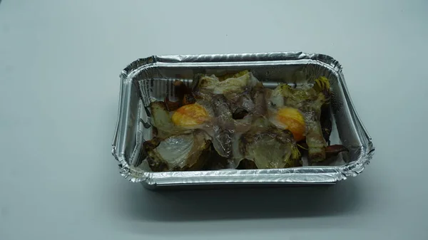 Artichokes, seasonal mushrooms, yolk and dewlap, in an aluminum container for takeaway food from a restaurant. I take takeaway food. Takeaway restaurants due to the covid-19 pandemic.