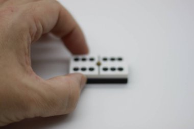 Adam elinde çifte altı domino taşını tutuyor. Beyazın üstünde.