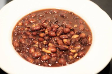 Kırmızı fasulye güveç, beyaz tabakta servis edilir.