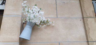 white flowers and a bouquet of roses on a brick wall.