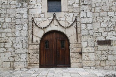 Taştan bir duvarda büyük bir zincir ile süslenmiş eski ahşap kapı.