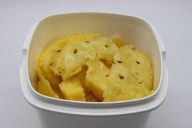 Olgun sarı ananas, beyaz bir kapta doğranmış.