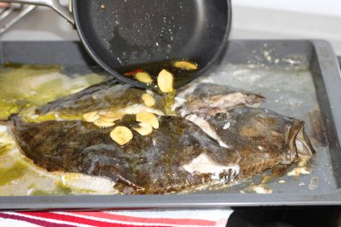 Fırında pişirilmiş bir turbotun üzerine sarımsaklı yeniden kızartılmış zeytinyağı döküyorum.
