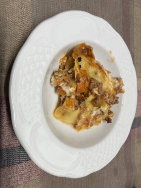 Beyaz bir tabakta servis edilen lazanya porsiyonu.