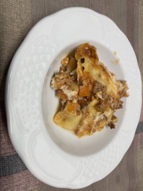 Beyaz bir tabakta servis edilen lazanya porsiyonu.