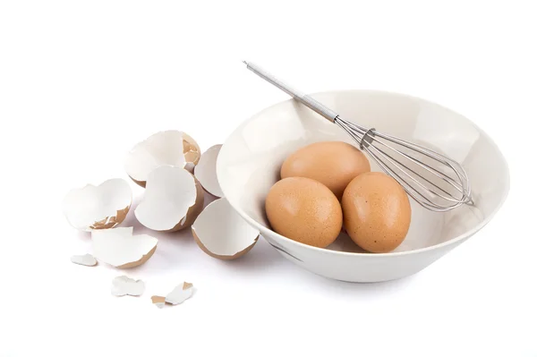Üç yumurta bir kase yumurta kabukları ile ve çırpma teli izole