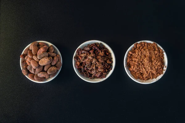 Cacao beans seeds, Cacao nibs and cacao powder isolated on black background.