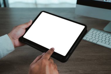 Eller tahta masada boş beyaz ekranlı dijital tablet tutuyor, parmak dokunuşu ekranı, arka planda klavyeli çalışma alanı, UI için kopyalama alanı, uygulama, tasarım modelinizi değiştirir