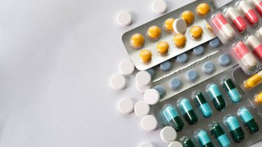 Beyaz arka planda renkli ilaç hapları ve kapsüller, antibiyotikler, reçeteli ilaçlar ve tıbbi tedavi alanlarında ilaç konsepti.