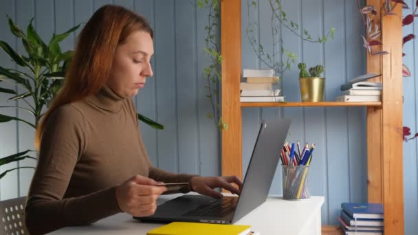 Woman sit at desk use laptop holding plastic card having problems, transaction rejected, not enough money on bank account. On-line payment failure, internet scam fraud theft victim concept — 图库视频影像