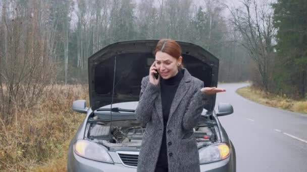 Droevige vrouw met telefoon aan haar oor beginnen te huilen in de buurt van auto-ongeluk scène met auto signaal lichten knipperen op de achtergrond — Stockvideo
