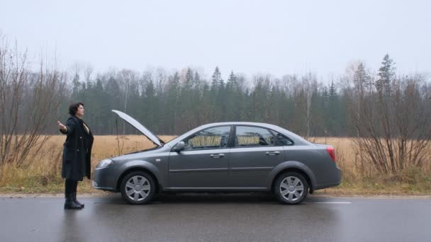 Femme adulte essayant d'arrêter une voiture dans la forêt. — Video