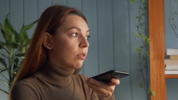 Frau sitzt am Arbeitstisch und hält Smartphone in der Hand, um mit Freundin über Lautsprechertelefon zu sprechen, Telefon-App benutzt, Voicemail-Antwort hinterlassen, Sprachnachricht an Kollegin senden — Stockvideo