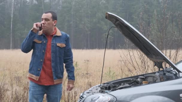 Triste hombre de pie cerca del coche roto y llamando a los servicios de asistencia del coche. — Vídeos de Stock