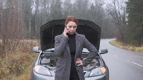 Ung kvinna ringer bilassistans står vid haveri bil på vägen — Stockvideo