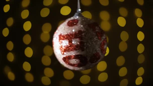 Weihnachtsdekoration, Kugel hängt auf dem Bokeh-Hintergrund blinkender Lichter. — Stockvideo