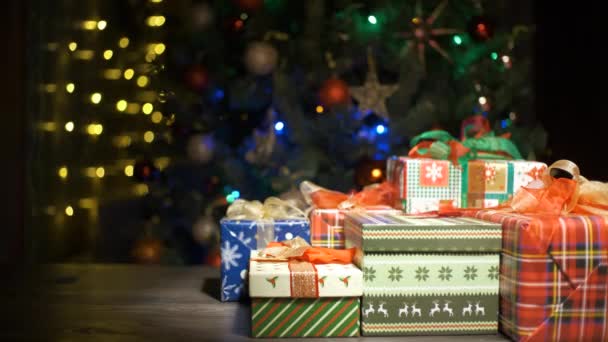 Hermosos regalos de Navidad en una mesa en casa y árbol con luces en el fondo, festividad y concepto de vacaciones — Vídeo de stock