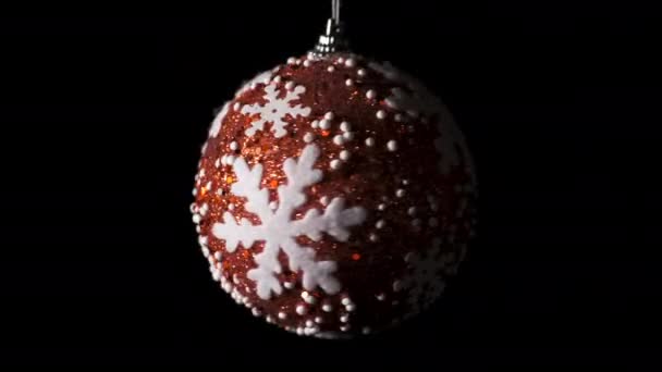 Rote Weihnachtskugel mit weißen Sternen auf dunklem Hintergrund. Weihnachts- und Neujahrskonzept. — Stockvideo
