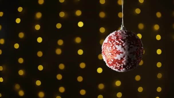 Bal rojo navideño con estrella blanca sobre un fondo bokeh guirnalda. Copiar espacio. Bokeh. Luces de decoración abstracta estrella, multicolor, brillo fondo borroso. — Vídeo de stock