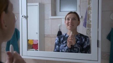 Hamile bir kadın banyoda hamilelik testi çubuğu tutuyor. Hamile bir kadın, bebeğin pozitif sonuç için heyecanlanmasını bekliyor ve şaşırıyor.