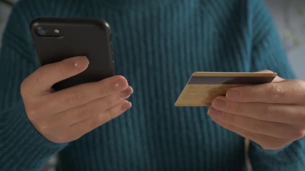 Vista de cerca. La mujer sostiene la paga del teléfono celular en línea con tarjeta de crédito de plástico. E-shopping con el gadget moderno, cliente hace el pago seguro del Internet — Vídeos de Stock