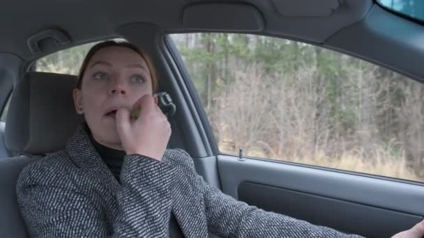 Завантажена жінка робить макіяж під час водіння автомобіля — стокове відео