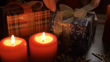 Kadın elleri Noel süsleriyle süslenmiş bir masaya Noel hediyesini koyar ve tamamlar. Noel ve Yeni Yıl kavramı