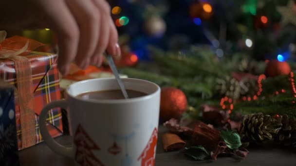 Горячий какао в окружении зимней елки на деревянном столе. Концепция уютного праздника и Нового года. 4K — стоковое видео